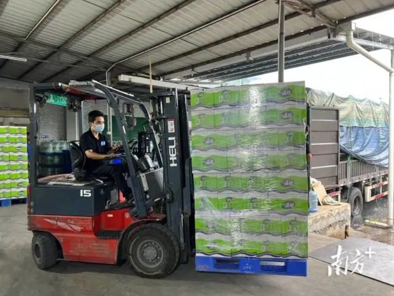 一箱箱饮用水由工人开着叉车搬运到集装箱内。 南方+ 张婧媛 拍摄 图片