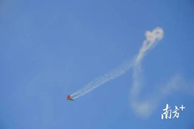 纸飞机编队飞行下挂的彩烟为天空画上了亮丽的色彩。 图片